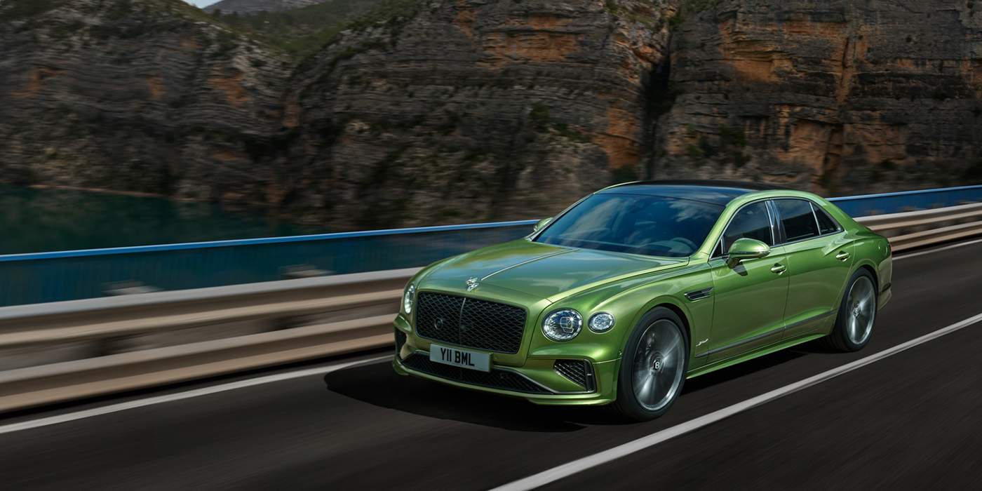 Bentley Yerevan Bentley New Flying Spur Speed v8 hybrid sedan driving dynamically on a mountain road in Tourmaline Green paint