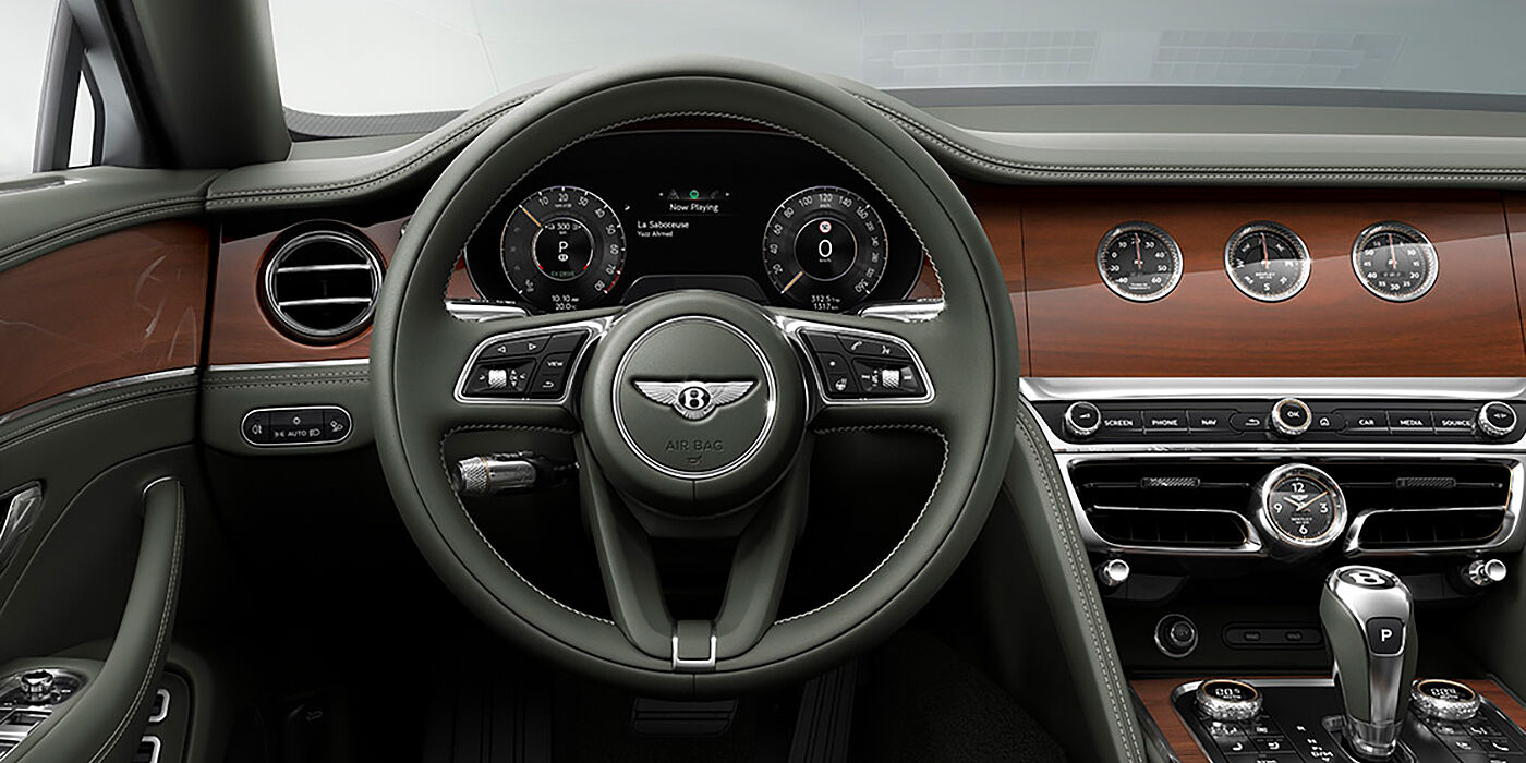 Bentley Yerevan New Bentley Flying Spur sedan front cabin in Cumbrian Green hide and Crown Cut walnut veneer showing steering wheel and Rotating Display with three clocks on face
