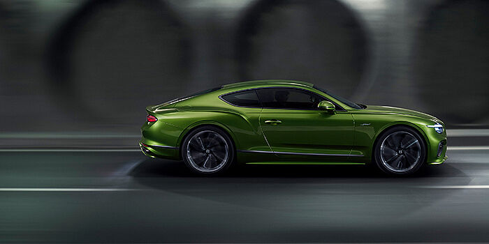  Bentley Yerevan Bentley Continental GT coupe in Tourmaline Green paint driving in profile on a dark road