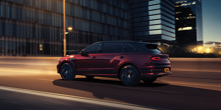 Bentley Yerevan Bentley Bentayga Extended Wheelbase Mulliner SUV in Cricket Ball red paint driving dynamically in city at night