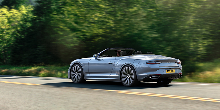 Bentley Yerevan New Bentley Continental GTC convertible side view in Silverlake paint with 22 inch ten spoke wheels driving dynamically on a country road